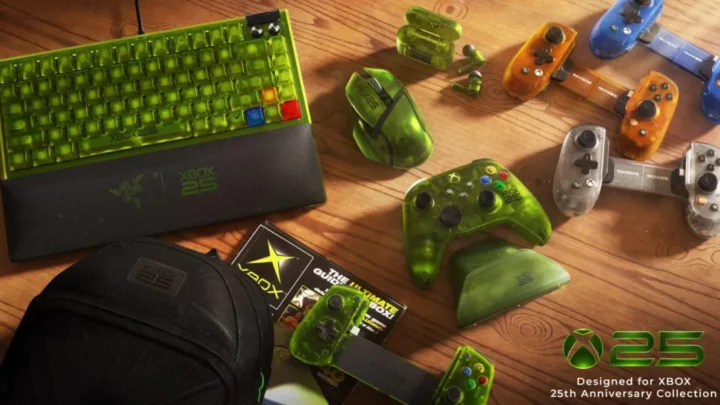 Coleção de periféricos temáticos em tons de verde e preto sobre mesa de madeira: teclado, controles, headset, mouse, mochilas e outros itens com logotipo comemorativo do 25º aniversário do Xbox