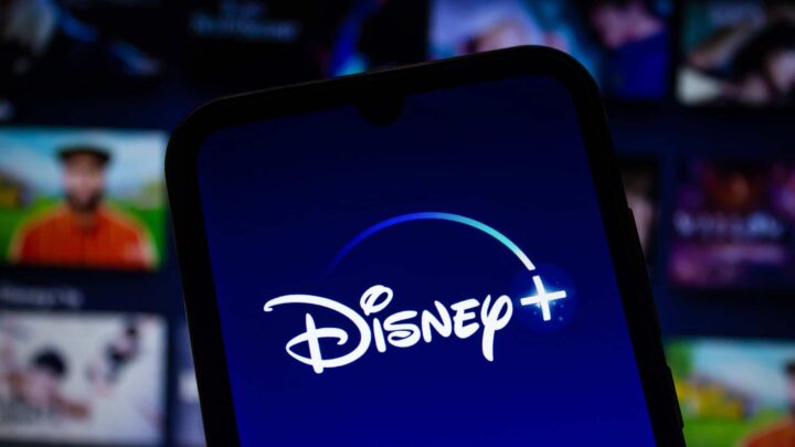 Logotipo do Disney+ exibido na tela de um smartphone, com a plataforma de streaming ao fundo desfocada
