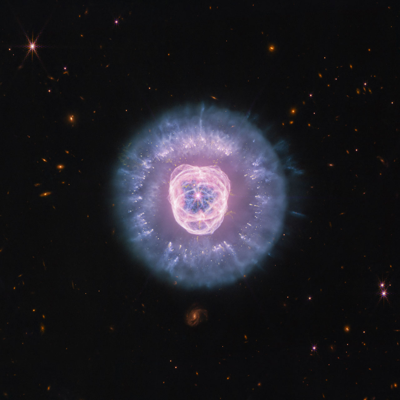 Imagem do telescópio James Webb mostra nebulosa planetária com núcleo brilhante em tons de rosa e rosa-claro, envolvido por estrutura azulada e rodeado por