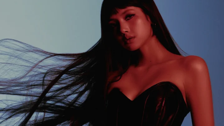 Mulher com cabelo longo preto em movimento usa top preto em sessão de fotos com iluminação vermelha e fundo azul