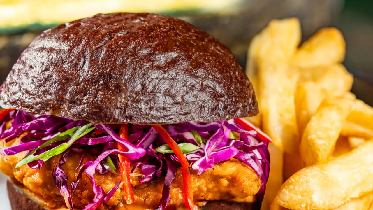 Devilish Crispy Chicken Sandwich: maionese apimentada, repolho roxo e pimenta Fresno em pão kaiser preto, servido com batatas fritas