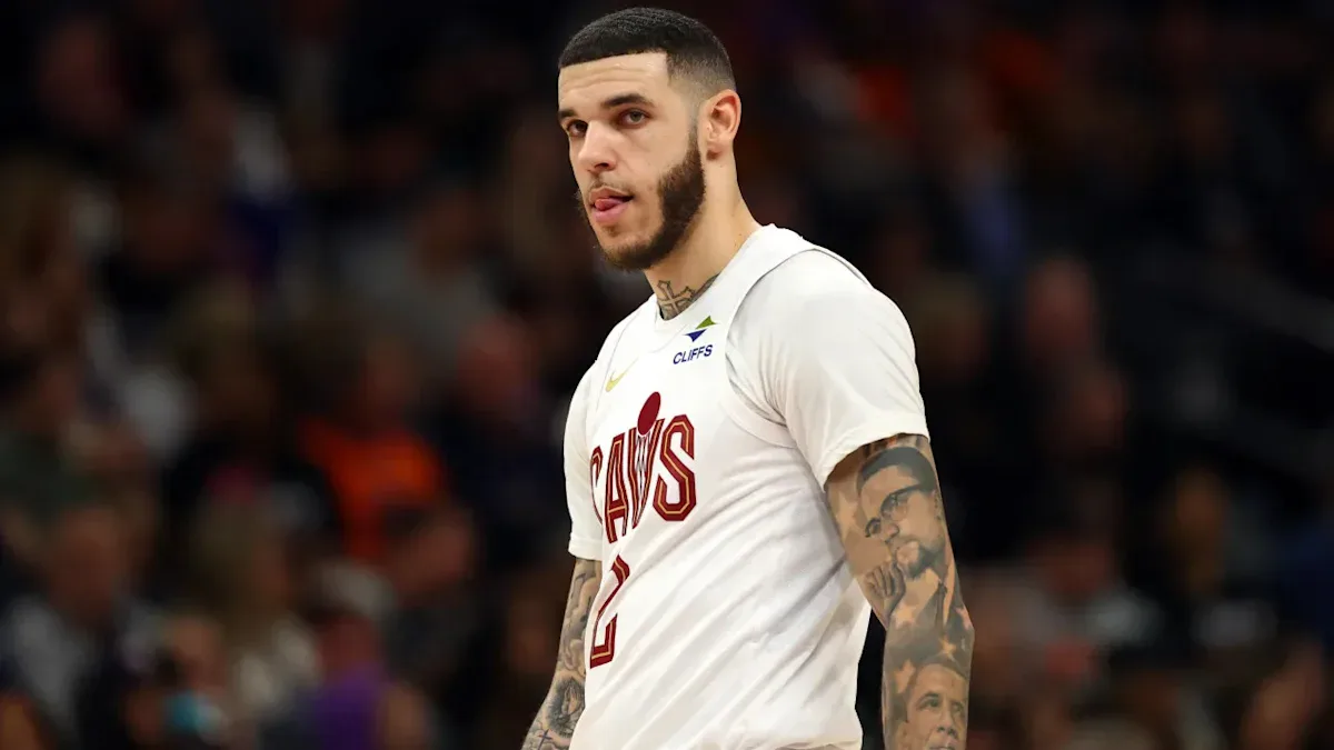 Jogador de basquete com uniforme branco e vermelho durante partida em quadra coberta com público ao fundo