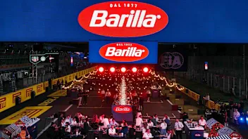 Evento de F1 recebe decoração temática com logos da marca de alimentos Barilla, enquanto público ocupa arquibancadas na pista de corrida