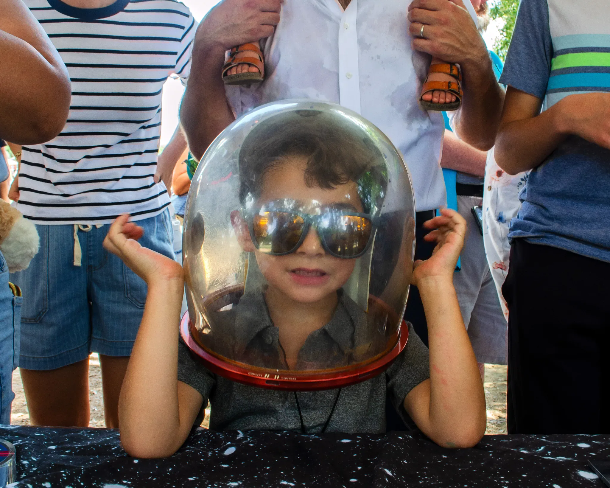 Participantes do Festival do Japão no Hermann Park, em Houston, experimentam luvas e um capacete de astronauta reais enquanto aprendem sobre missões da NASA, em 12 de setembro de 2026.
