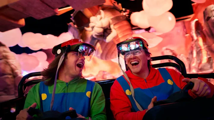 Dois meninos sorriem e riem um para o outro enquanto andam no Mario Kart: Bowser's Challenge no Universal Epic Universe