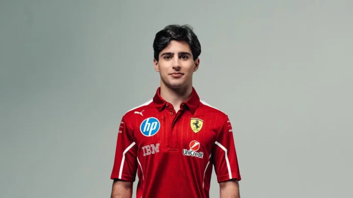 Jovem piloto de F2 posa para foto de apresentação usando uniforme vermelho de equipe com patrocinadores