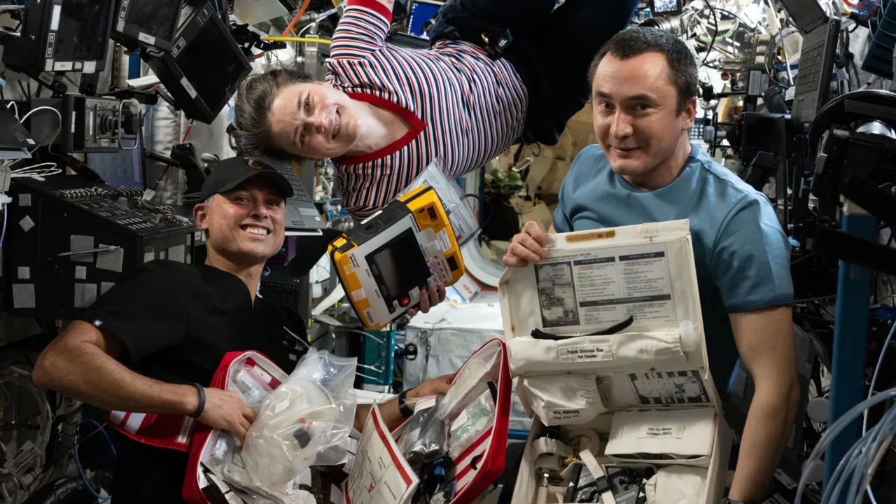 iss075e0088825 (4 de setembro de 2026), os engenheiros de voo da Expedição 75 Anil Menon, da NASA, e Anna Kikina e Pyotr Dubrov, da Roscosmos, sorriem para um retrato enquanto verificam equipamentos médicos de emergência dentro do módulo de laboratório Destiny da Estação Espacial Internacional.