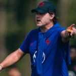 Técnico gesticula durante treino com uniforme azul da seleção americana de futebol