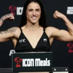 Lutadora de MMA exibe músculos flexionando os braços durante pesagem oficial do UFC, em evento transmitido pela ESPN