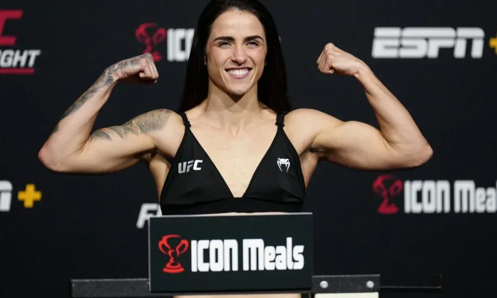 Lutadora de MMA exibe músculos flexionando os braços durante pesagem oficial do UFC, em evento transmitido pela ESPN