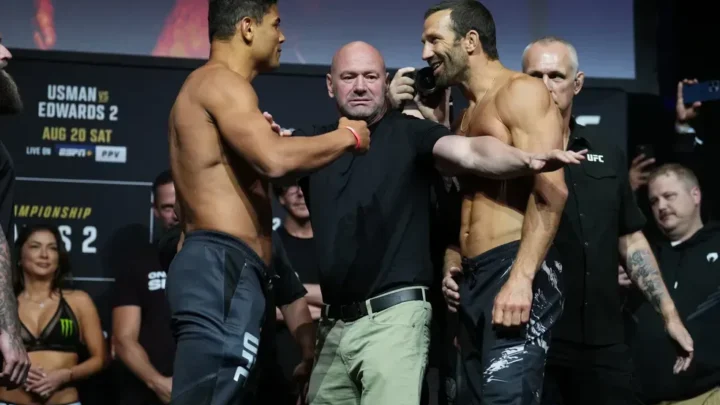 Dois lutadores shirtless em postura de confronto durante pesagem do UFC, com árbitro entre eles e equipe ao fundo