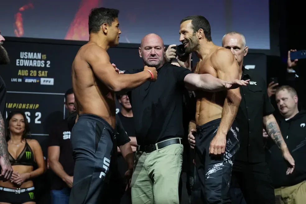 Dois lutadores shirtless em postura de confronto durante pesagem do UFC, com árbitro entre eles e equipe ao fundo