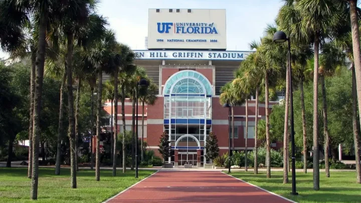 Fachada do estádio Ben Hill Griffin com o logo da Universidade da Flórida e placa com os títulos de campeão nacional conquistados em 1996 e 2006, cercado por palmeiras