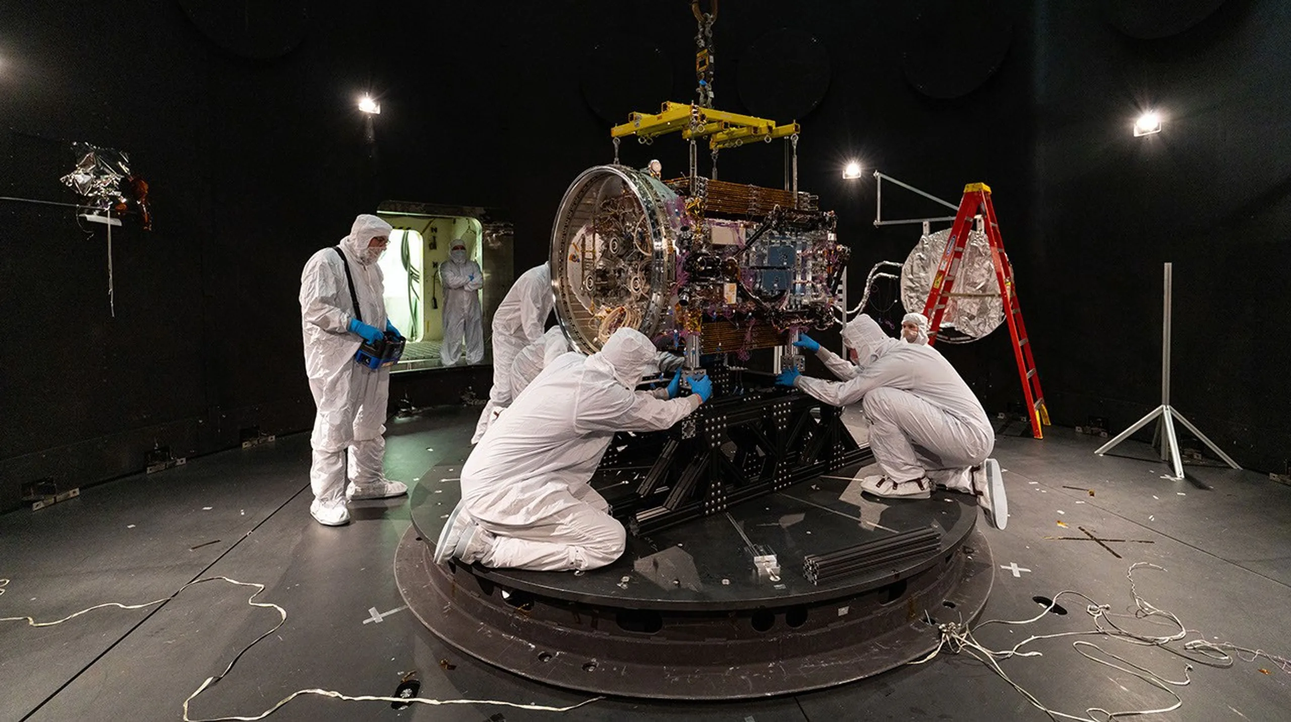 Engenheiros da Katalyst fixam a LINK a uma placa-base dentro do Simulador de Ambiente Espacial no Centro de Voo Espacial Goddard da NASA, em Greenbelt, Maryland, em 28 de abril de 2026. Depois que todo o ar foi bombeado para fora da câmara de 27 pés de diâmetro, a equipe praticou o acionamento dos propulsores iônicos do satélite e operou um dos braços robóticos enquanto passavam por ciclos de temperaturas quentes e frias semelhantes às do espaço.