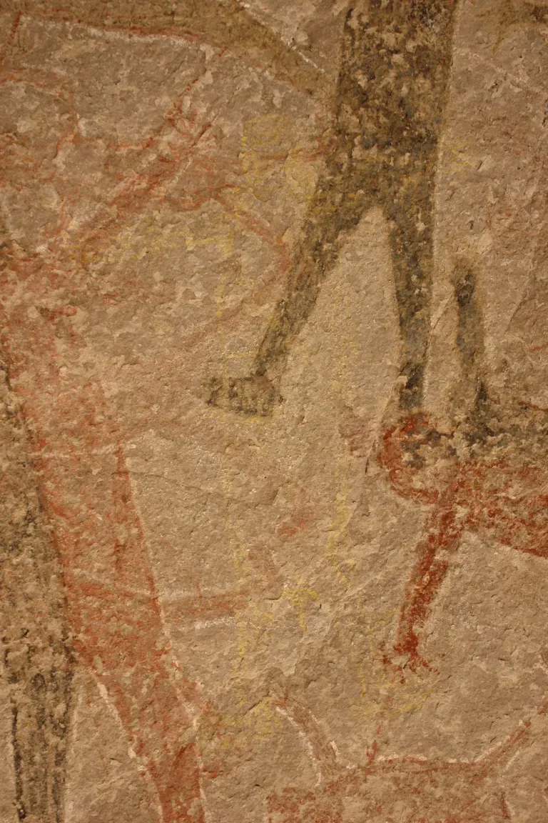 Uma parede com uma série de figuras humanoides desbotadas pintadas nela.