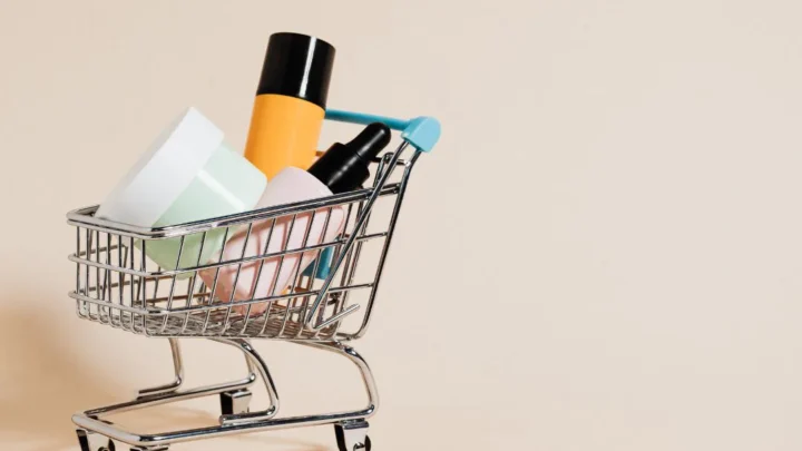 Carrinho de compras em miniatura contém produtos de beleza e higiene pessoal contra fundo bege