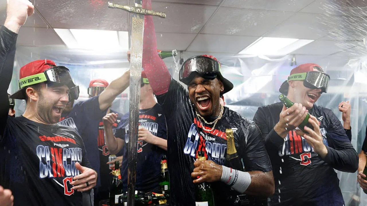 Integrantes de time de beisebol comemoram dentro do vestiário após clinchar vaga nos playoffs, com champanhe sendo derramado sobre eles