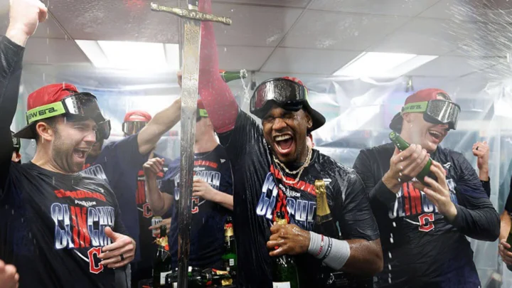 Integrantes de time de beisebol comemoram dentro do vestiário após clinchar vaga nos playoffs, com champanhe sendo derramado sobre eles