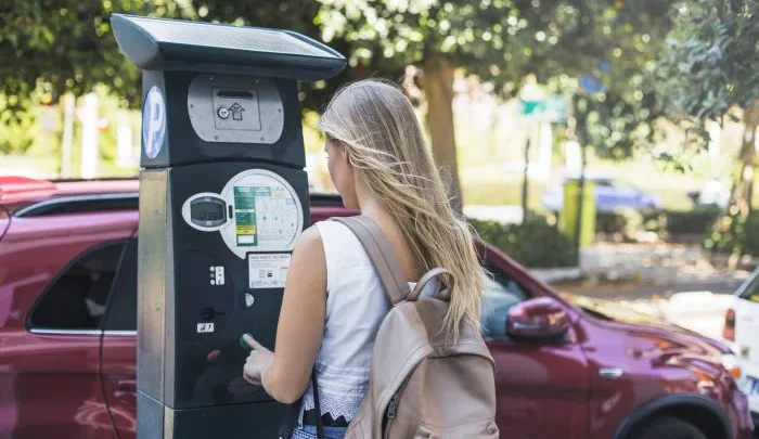 Mulher usa parquímetro em via pública de Orlando para efetuar pagamento de estacionamento em área de Downtown
