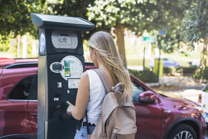 Mulher usa parquímetro em via pública de Orlando para efetuar pagamento de estacionamento em área de Downtown