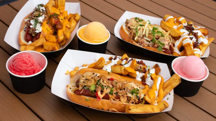 Três cachorros-quentes do Fat One's no Universal CityWalk ao lado de três sabores de Italian ice: cereja, manga e algodão-doce