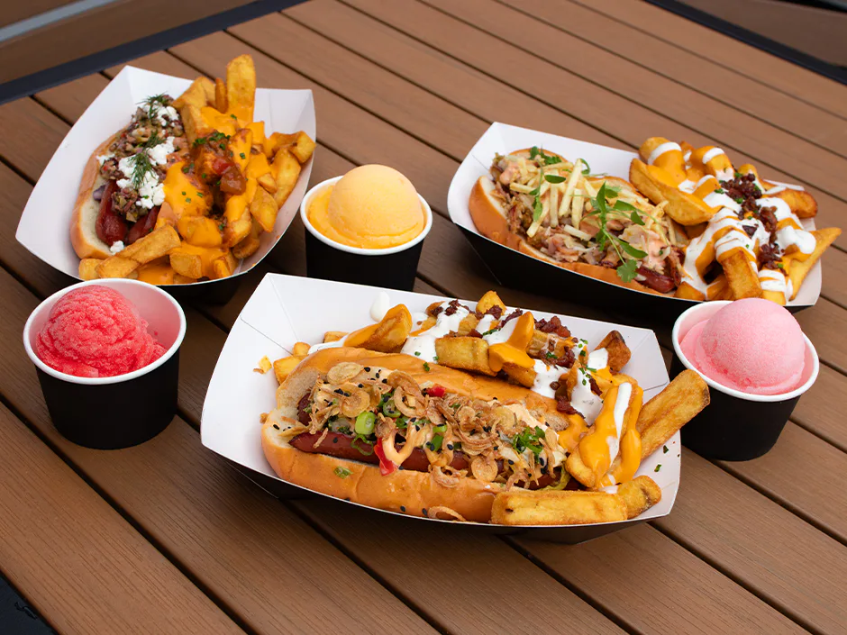 Três cachorros-quentes do Fat One's no Universal CityWalk ao lado de três sabores de Italian ice: cereja, manga e algodão-doce