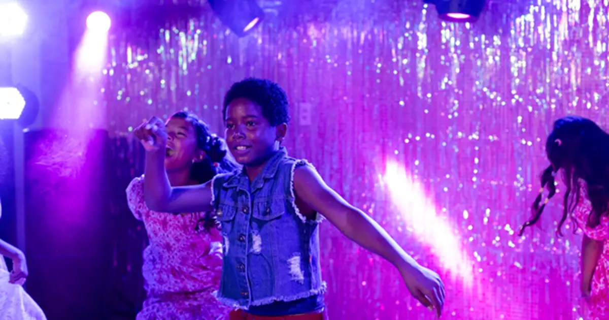 Cenas do filme Feito Pipa mostram crianças dançando em ambiente com iluminação roxo-rosa e cortina de lantejoulas brilhantes ao fundo