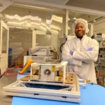 O Dr. Nehemiah Williams, gerente de projeto da demonstração na NASA, se prepara para iniciar os testes do hardware de voo da missão em uma sala limpa no Centro de Voo Espacial Marshall da NASA, em Huntsville, Alabama. A missão demonstrará um único sistema de propulsão não tóxico que combina