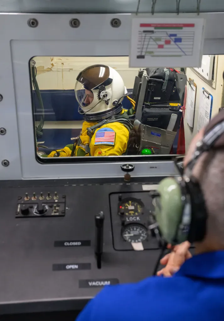 O candidato a astronauta da NASA Adam Fuhrmann senta-se dentro da câmara de altitude no Centro de Treinamento Sonny Carter da NASA, em Houston.