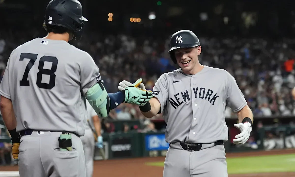 Dois jogadores do New York Yankees se cumprimentam durante partida contra o Arizona Diamondbacks no estádio, com público ao fundo