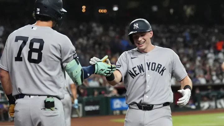 Dois jogadores do New York Yankees se cumprimentam durante partida contra o Arizona Diamondbacks no estádio, com público ao fundo