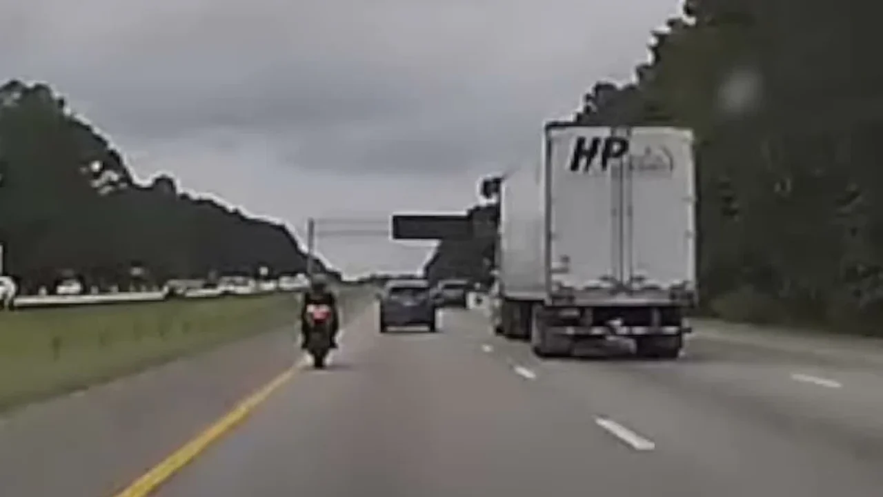 Câmera da viatura mostra a moto em alta velocidade numa rodovia, ao lado de um caminhão, durante a perseguição