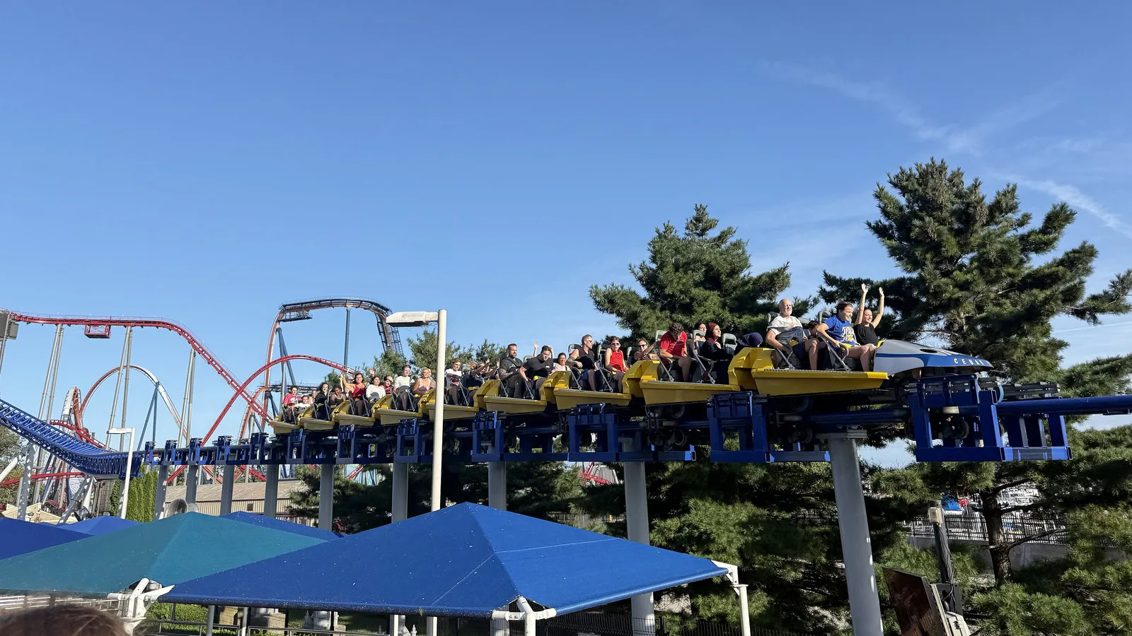 Passageiros com os braços para cima em um trem amarelo da Millennium Force, no trecho final do percurso