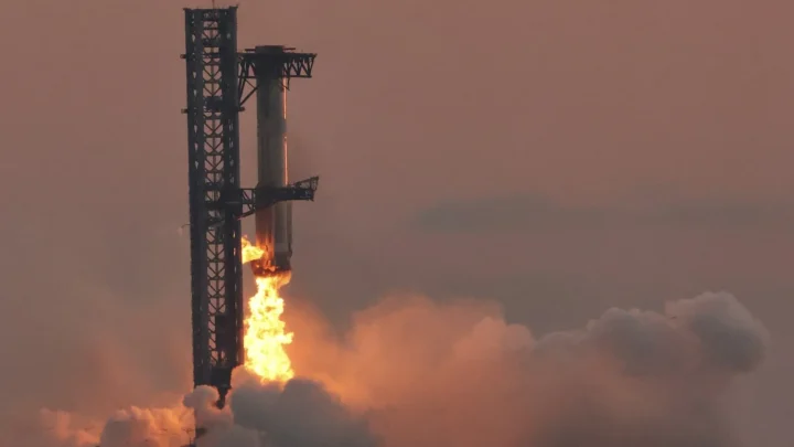 Braços da torre de Starbase, no Texas, seguram o propulsor Super Heavy no 5º voo de teste da Starship, em outubro de 2024 (imagem de arquivo)
