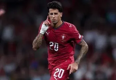 Jogador em uniforme de seleção europeia vermelha na número 20 durante partida de futebol em estádio com público ao fundo