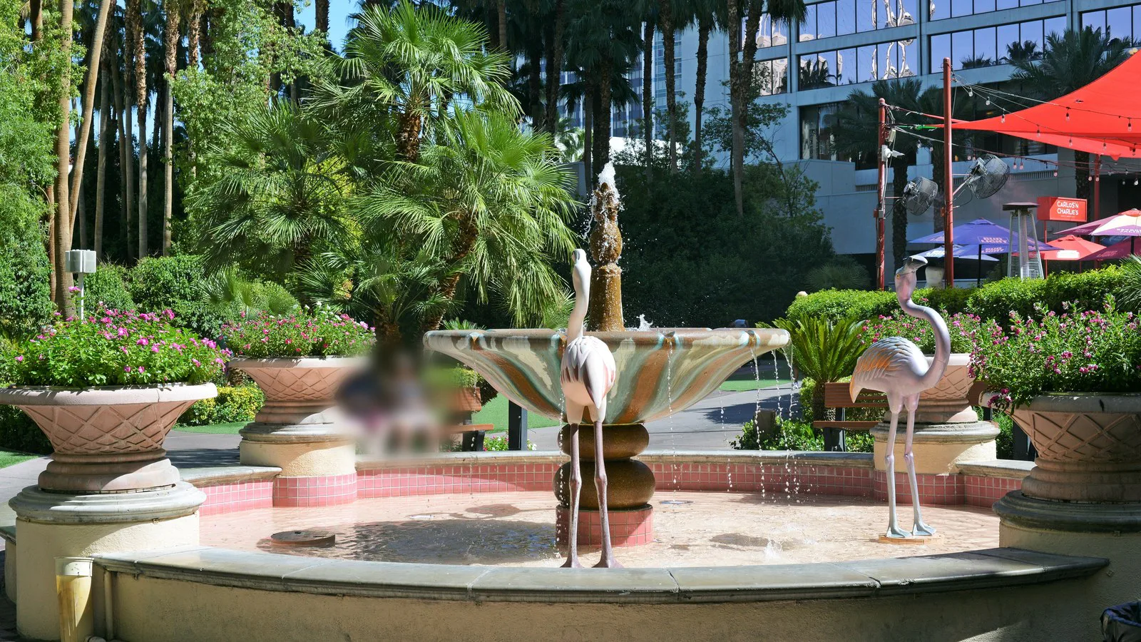 Fonte com esculturas de flamingos cercada de palmeiras e vasos de flores no hotel Flamingo, em Las Vegas, em foto de 2022