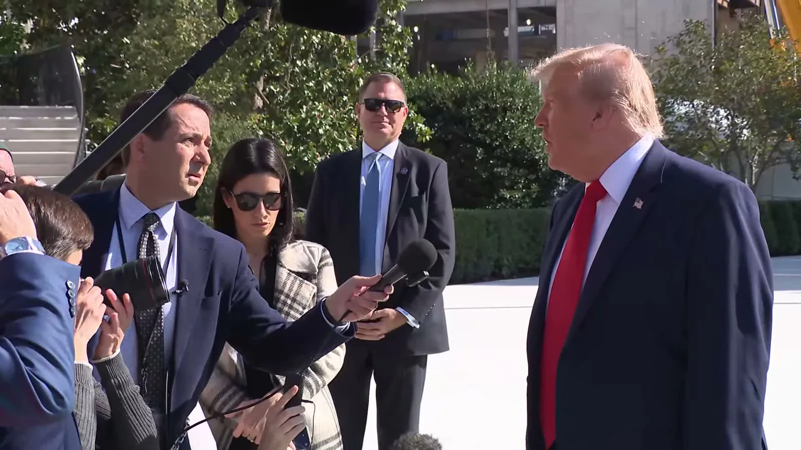 Donald Trump, de terno azul e gravata vermelha, ouve a pergunta de um repórter cercado de jornalistas e microfones no gramado sul da Casa Branca, na sexta-feira, 23 de outubro de 2026