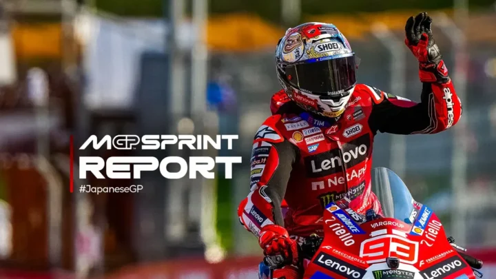 Piloto de motociclismo em traje de corrida vermelho com patrocinadores acena para a multidão em circuito durante competição