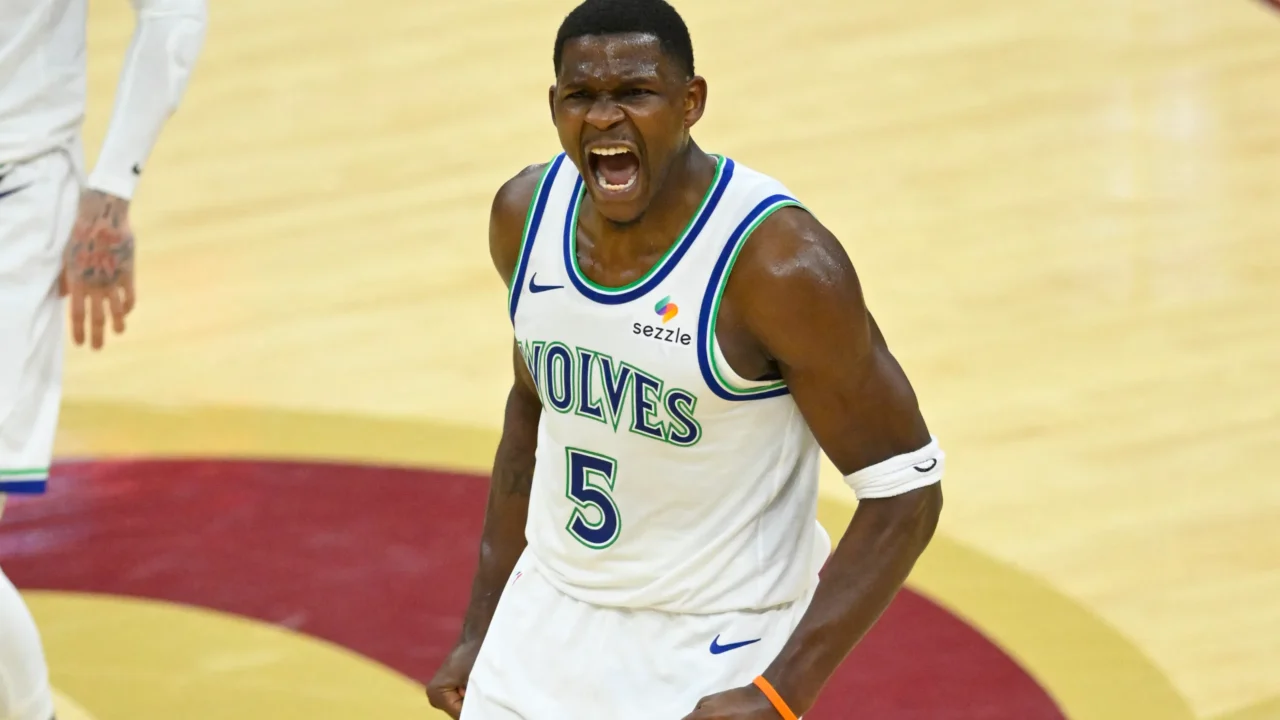 Jogador de camisa branca com detalhes azuis e verdes, número 5 e a palavra "Wolves", grita e cerra os punhos em quadra