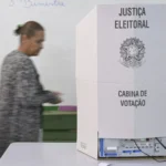 Pessoa passa ao lado de uma cabina de votação da Justiça Eleitoral na 17ª Zona Eleitoral, no Gama, no Distrito Federal, no 1º turno, em 4 de outubro de 2026
