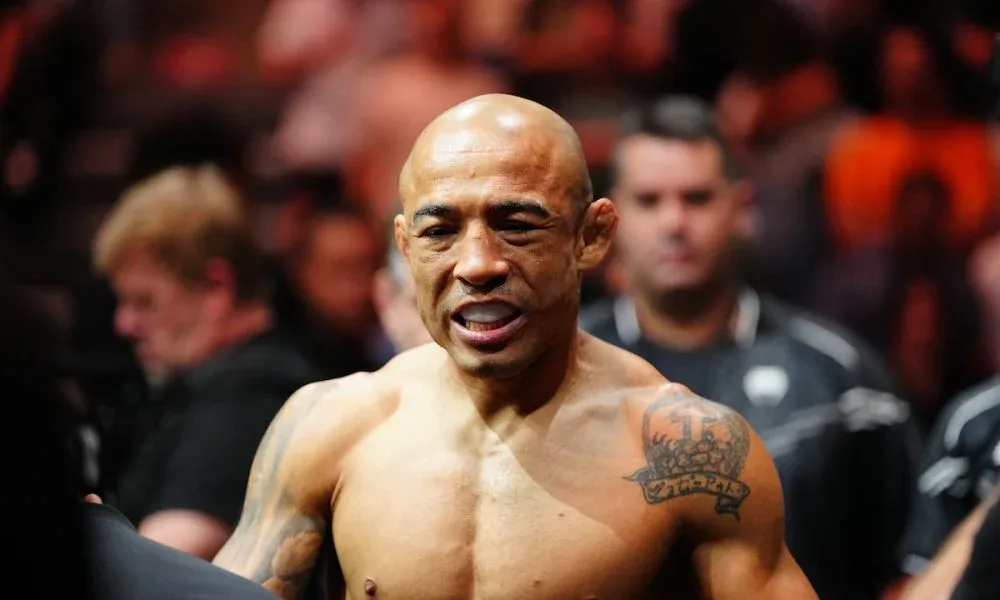 Lutador sem camisa, com tatuagem no ombro, participa de confronto de grappling cercado por espectadores em evento no Equador
