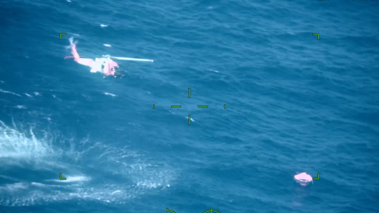 Imagem aérea do helicóptero da Guarda Costeira sobre o mar, com uma balsa salva-vidas abaixo