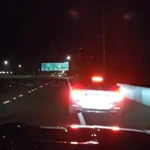 Imagem da câmera da viatura mostra, de madrugada, as lanternas de um carro à frente na rodovia
