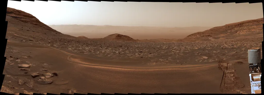 O rover Curiosity da NASA capturou esta vista olhando de volta para o chão da Cratera Gale em Set5, 2026. Apenas nove dias antes, o rover havia marcado 1 quilômetro de ganho de elevação acima do chão da cratera desde que começou sua ascensão do Monte Sharp em 2014.