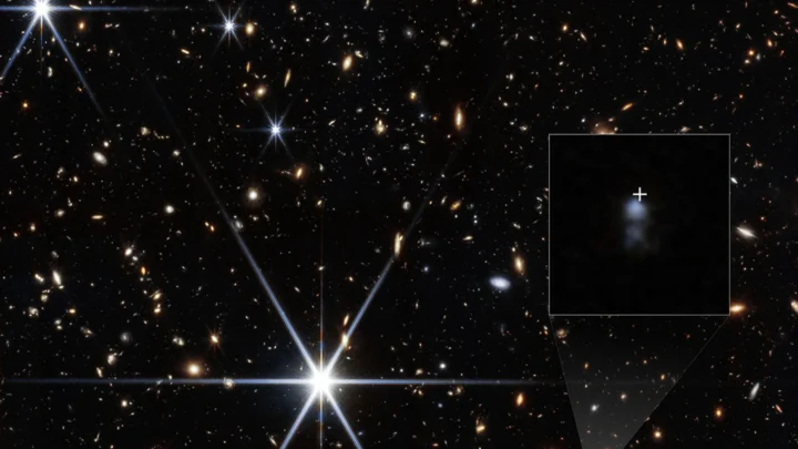 A NIRCam (Câmera de Infravermelho Próximo) do Telescópio Espacial James Webb da NASA conseguiu detectar a galáxia hospedeira da explosão rápida de rádio chamada FRB 20240304B, cuja localização é mostrada pela cruz branca. Eles descobriram que se trata de uma pequena galáxia anã formando estrelas