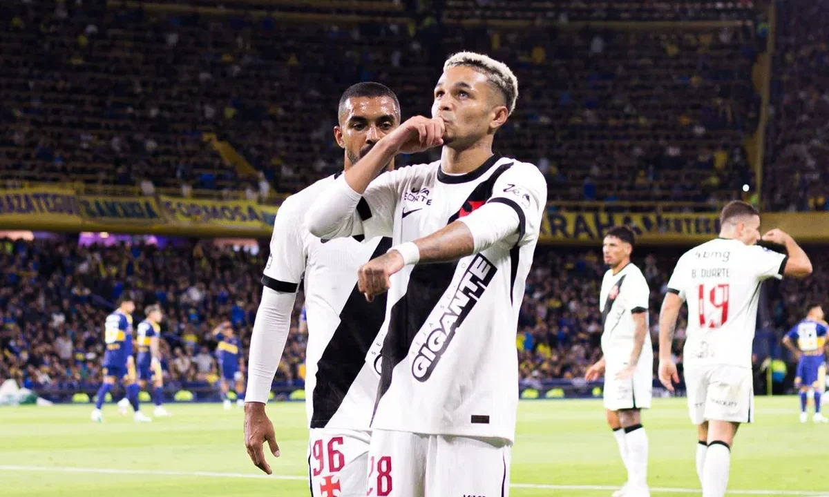 Jogador do Vasco comemora gol com a camisa branca do clube, com torcedores de Boca Juniors ao fundo em estádio lotado
