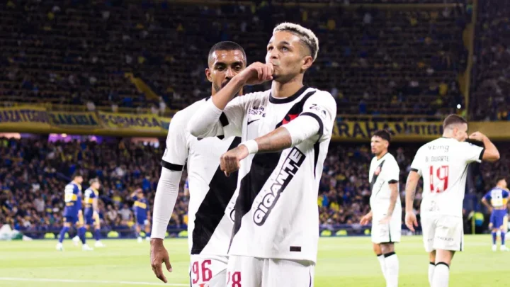 Jogador do Vasco comemora gol com a camisa branca do clube, com torcedores de Boca Juniors ao fundo em estádio lotado