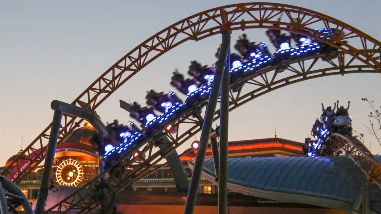 Foto de arquivo de abril de 2025, ao entardecer, de um trem da montanha-russa Stardust Racers com as luzes acesas no Epic Universe, em Orlando; a foto não mostra a fila nem o ventilador