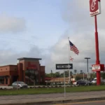 Foto de arquivo de uma unidade do Chick-fil-A em Lake City, na Flórida, com placa vermelha alta, bandeira dos EUA e estacionamento à beira da avenida