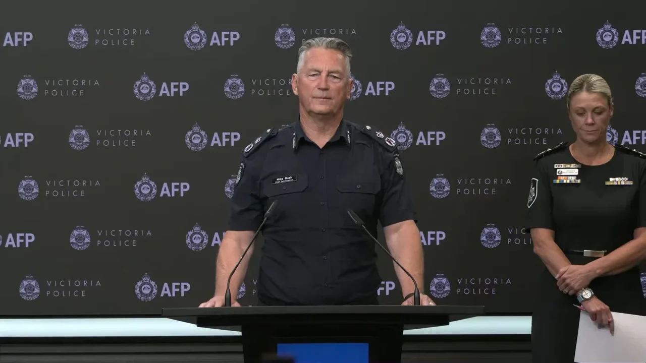 O comissário-chefe da polícia de Victoria, Mike Bush, ao púlpito, ao lado da comissária da Polícia Federal australiana, Krissy Barrett, em coletiva, em 21 de outubro de 2026